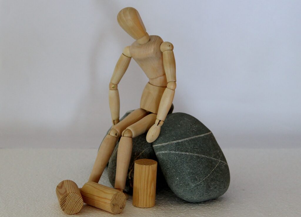Drewniana figurka człowieka odpoczywającego na kamieniu, fot. Counselling (Ulrike Mai), Pixabay 980802